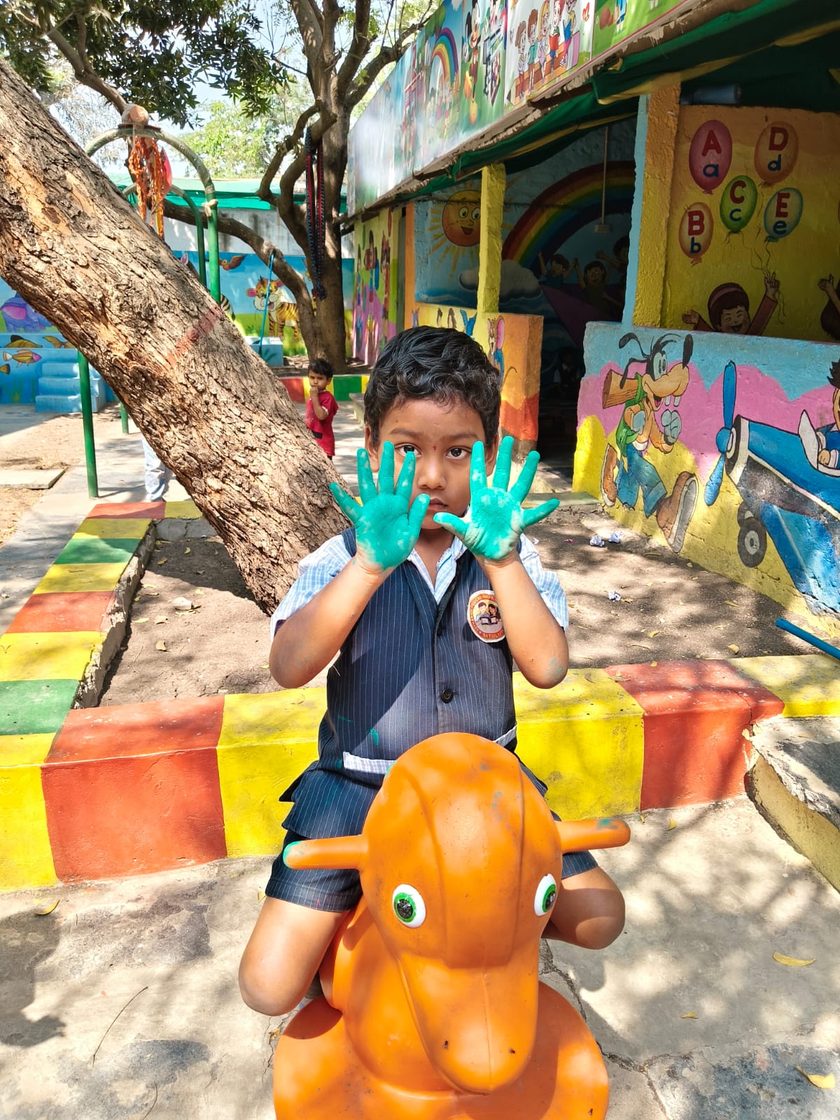 Child with green painted hands on a play horse